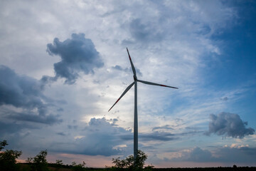 Selective blur on a windmills in the fields of Voivodina, in Serbia, during a sunny night, atdusk. This windfarm, made of wind turbines, is aimed at producing renewable energy and green electricity