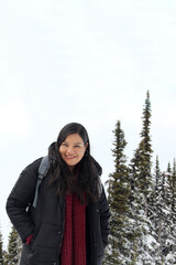 Latin adult woman celebrates her arrival at the top of the snowy mountain very warm because it is very cold, happy to meet her goals and objectives
