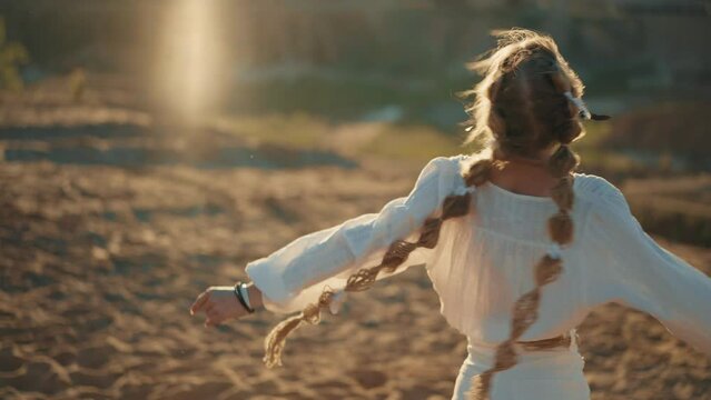 4K Slow-mo video. Happy young blond woman with braid spining on blue sky  background. Sunset cinematic consept. National ethnic costume. Freedom and happiness atmosphere.
