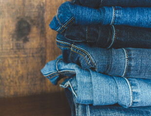 Blue denim jeans folded and piled up in a stack with a rustic wooden background - Powered by Adobe