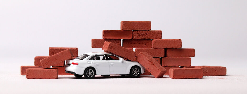 The concept of the dangers of car accidents. A miniature car that collided with a red brick.
