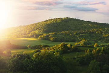 Green hill lit by sun setting down.Spring landscape. - Powered by Adobe