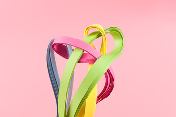 Colorful paper striped  in curls and twisted on pink background.