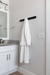 White bath robe hanging on a hook in a bathroom 