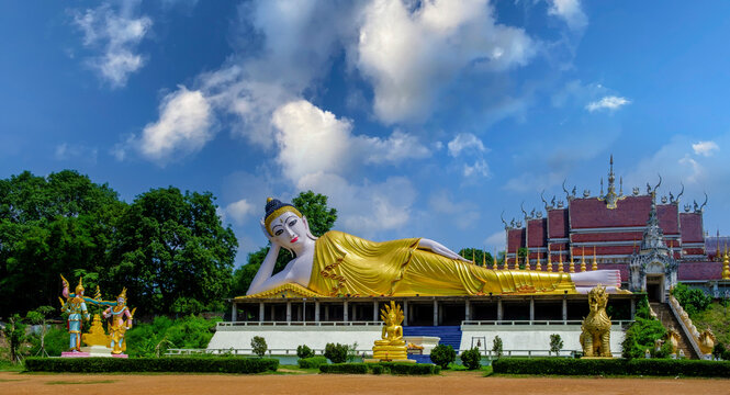 Big reclining golden Buddha on the open air with white clouds and blue sky on background. Travel concept.