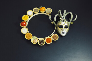 Theatrical mask and tartlets with spices and vegetables. Black pepper, cumin, turmeric, sesame, red...