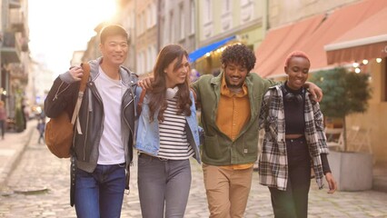 Group of multi-ethnic happy friends walking on street and talking in good mood. Male and female young joyful people hugging and smiling outdoors. Leisure time, positive emotions. Friendship concept - Powered by Adobe