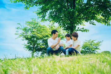 晴天の緑地に座る親子