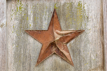 Rusty red metal star on a wooden wall