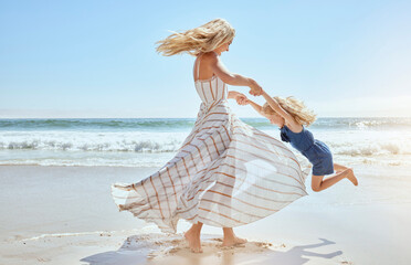 Happy mother swinging and spinning cute daughter in circles by the arms at the beach. Playful,...
