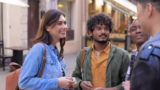 Close up portrait of positive multi-ethnic males and females chatting and smiling outside in city. Young handsome man and pretty woman gathered together with friends at street. Leisure, communication