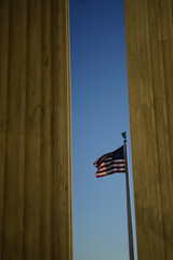 American flag in the wind from the columns of Supreme Court building entrance in Washington DC, USA