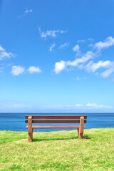 Beautiful beach view from a bench with copy space on a summer day with a blue sky background. Peaceful and calm seascape with a seat in a coastal vacation location. Scenic land of sea or ocean shore