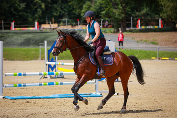Horse with rider galloping in the riding arena..