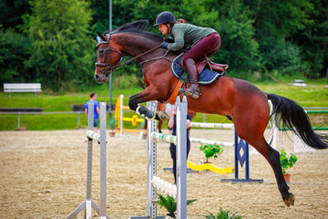 Show jumper with horse during the flight phase over the obstacle, side view..