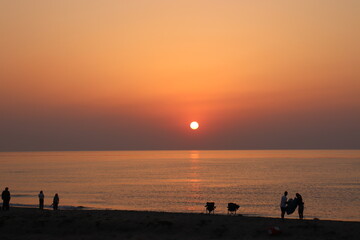 海に沈む夕日を見てテントをたたむ人々