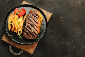 Striploin beef steak with french fries on dark background.