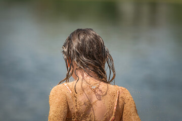 Beautiful little girl is playing on the beach with sand.