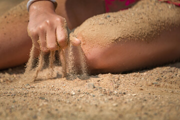 Beautiful little girl is playing on the beach with sand.