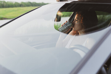 Naklejka premium beautiful young woman travel on the roads by car, stopped at the side of the road and look at the map, drink coffee from a thermos. Vacation concept