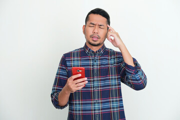 Adult Asian man try to remember something with eyes close while holding mobile phone