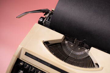 Typewriter with black paper on a pink background, vintage concept.