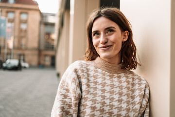 Young woman leaning against a wall and looking forward laughing