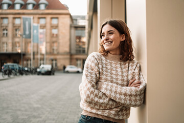 Young woman leaning against a wall and looking to the side laughing
