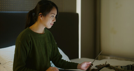 Woman work on laptop computer on bed at night