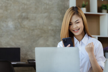 Woman gesturing and looking at mobilephone screen, businesswoman checking company monthly sales and pretending to be happy as sales meet planned targets according to policy. Sales management concept.