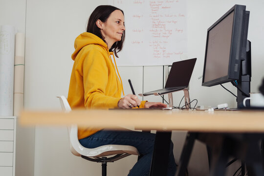 Business woman with yellow hoodie drawing with her tablet on computer