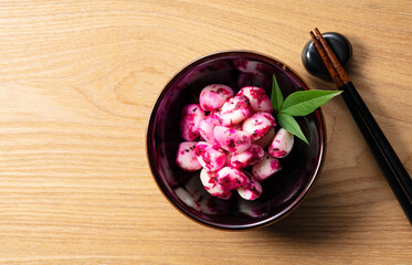 Pickled shiso bonito garlic on a plate placed against a wooden background.