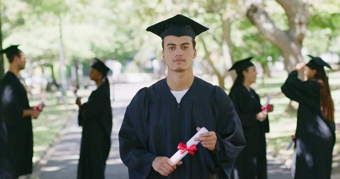 Portrait of a confident male graduate at a university or college campus holding his degree. A young male who received his honors or diploma at a graduation ceremony standing outdoors