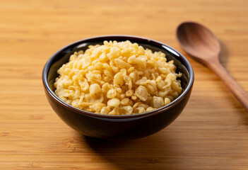 Tenkasu and wooden spoon served in a bowl placed on a wooden background.