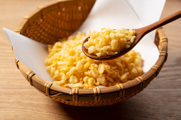 Tenkasu served in a colander placed on a wooden background with a wooden spoon.