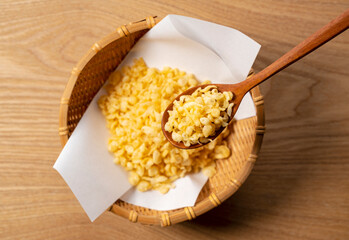 Tenkasu served in a colander placed on a wooden background with a wooden spoon.