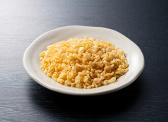 Tenkasu on a plate placed on a black background.