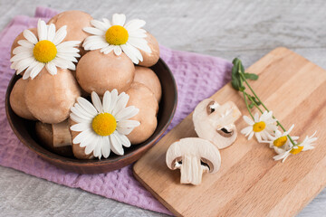 Fototapeta na wymiar Gray mushrooms are champignons in a basket. Decorated with field daisies