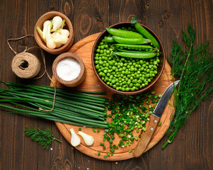vegetables on a dark wooden board top view, green onions, dill and peas on a wood background, concept of fresh and healthy food, still life