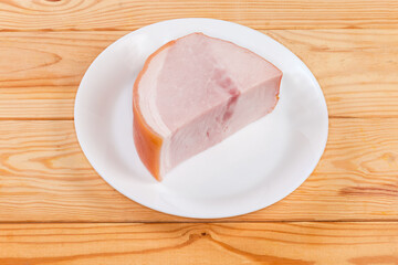 Piece of boiled smoked ham on dish on rustic table
