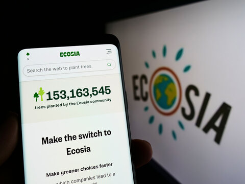 Stuttgart, Germany - 07-03-2022: Person holding cellphone with webpage of German search engine company Ecosia GmbH on screen in front of logo. Focus on center of phone display.