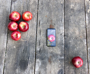 red apples and mobile phone on old, worn garden table - Powered by Adobe
