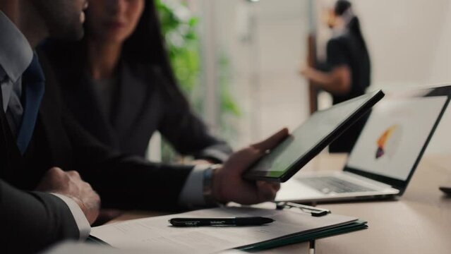 Two colleagues discuss data analyzing marketing using laptop or notebook having business conversation help coworker with corporate project sit at office desk.