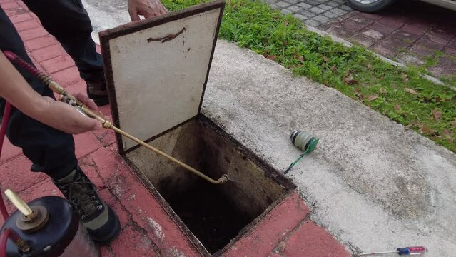 Mexican pest exterminator fumigating client's home sewage system full of cockroaches, Slowmotion Opening Sewage cover to put chemicals that kill the insects