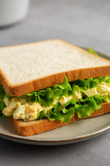 Homemade Egg Salad Sandwich with Lettuce on a Plate, side view.