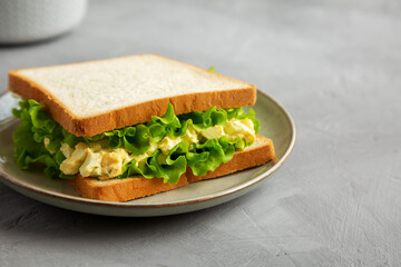 Homemade Egg Salad Sandwich with Lettuce on a Plate, side view. Copy space.