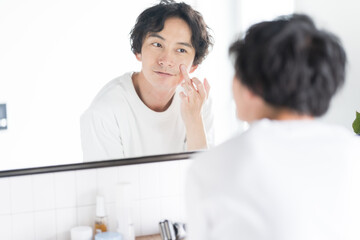 Fototapeta アジア人男性メンズビューティー、頬に手をあてて鏡を見ている obraz