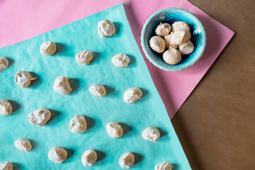 Homemade french milk-colored meringues on blue paper