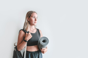 Fototapeta premium girl in a sports uniform and with an inventory on a gray background. The girl goes in for sports, fitness, yoga. Meditation, relaxation, mental health. Active lifestyle, personal care, health.