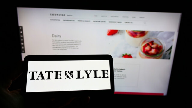 Stuttgart, Germany - 01-29-2022: Person holding smartphone with logo of British food processing company Tate Lyle PLC on screen in front of website. Focus on phone display.